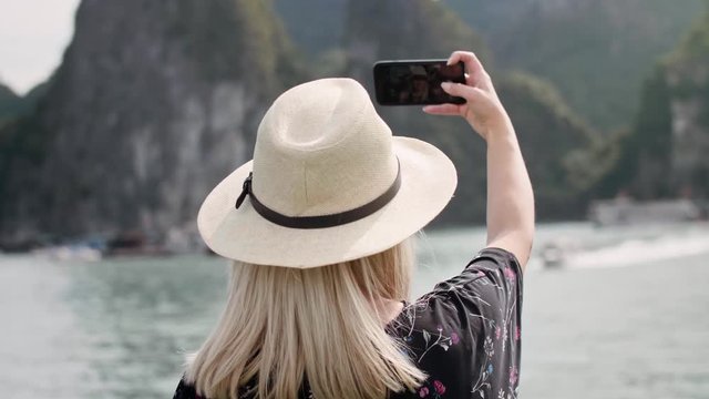 Handheld view of female tourist with mobile phone making selfie. Shot with RED helium camera in 8K