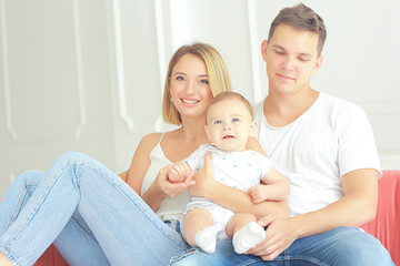 Fototapeta na wymiar baby with parents in a cozy house / healthy young family mom dad and baby, happiness smile