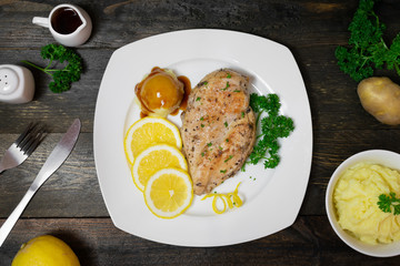 Baked chicken breast with lemon for fresh in white dish on wooden table.