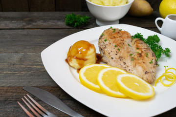 Baked chicken breast with lemon for fresh in white dish on wooden table.
