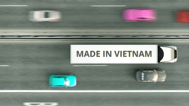 Aerial top down view of semi-trailer trucks with MADE IN VIETNAM text driving along the highway. Vietnamese business related loopable 3D animation