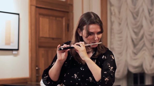 Young woman playing a piccolo flute, closeup portrait of a musician