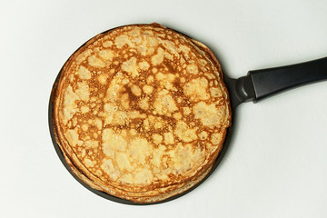 Homemade Russian pancakes on frying pan on white background. Top view.
