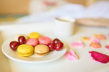 Side view of cup of coffee with tasty colorful macarons or macaroons on white tray. Romantic breakfast concept