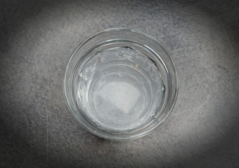 The glass is half full of water on grey table top view with space for text, filtered image