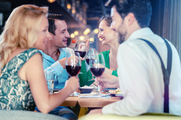People in a restaurant eating and drinking red wine