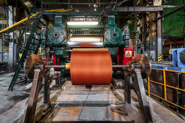 Wide orange polyamide canvas in a conveyor belt making machine.