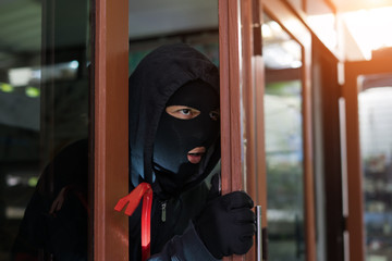 masked burglar with crowbar breaking and entering into a victim's home