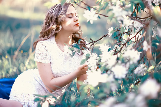girl sniffing flowers / fresh spring flowers of apple, portrait of a girl in a beautiful spring garden