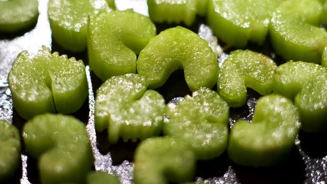 Chopped celery sauteeing on a black frying pan, healthy vegan food concept. Stock footage. Close up of pieces of green fresh celery on oily pan surface background.