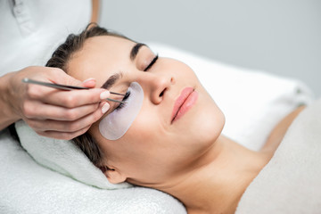 Woman receiving eyelash extension procedure, close up.