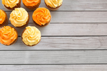 food, pastry and confectionery concept - cupcakes with buttercream frosting over grey wooden boards background
