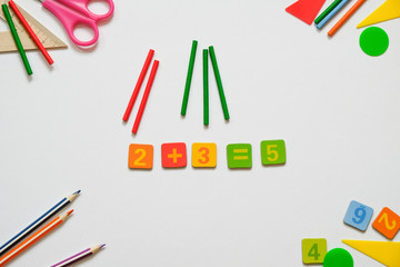 Math concept: colorful pens and pencils, number, calculating sticks in white background. Mathematics