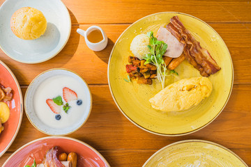 Fried egg with eggs benedict and omelette around bacaon ham sausage in plate