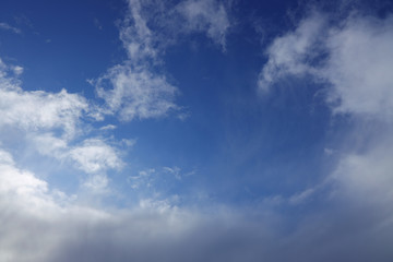 Blue sky background with light white cirrus clouds at the zenith.