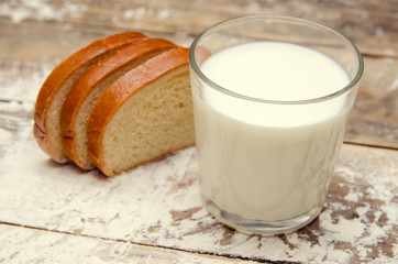 glass of milk and three slices of sliced loaf on a wooden background with flour close-up