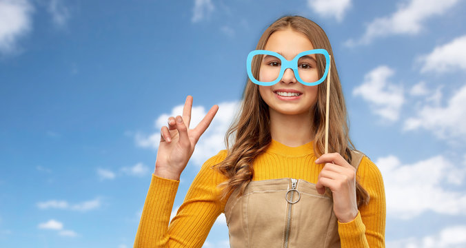 party props, photo booth and people concept - smiling red haired teenage girl with big glasses over blue sky and clouds background