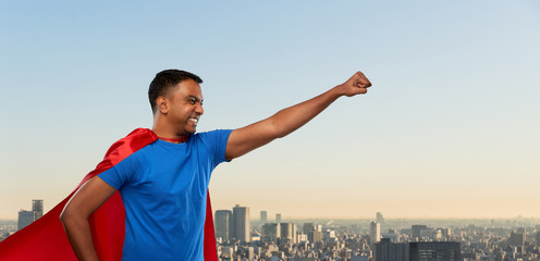 Fototapeta na wymiar super power and people concept - indian man in red superhero cape making winning gesture over tokyo city background