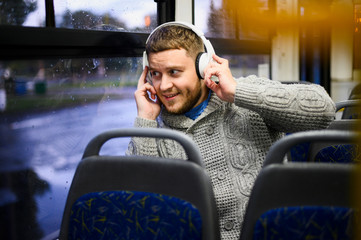 Young man with headphones on the seat of the bus