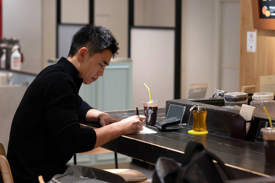 Young Asian male signs a document at a cafe in Tokyo, Japan