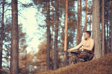 Fototapeta na wymiar hunting man / hunter with a gun hunting in the autumn forest, yellow trees landscape in the taiga