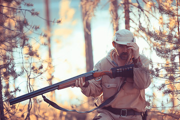 Naklejka premium hunting man / hunter with a gun hunting in the autumn forest, yellow trees landscape in the taiga