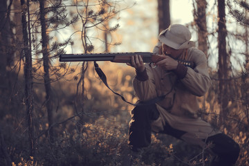 Naklejka premium hunting man / hunter with a gun hunting in the autumn forest, yellow trees landscape in the taiga