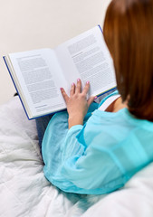 Fototapeta premium leisure and people concept - close up of woman reading book sitting on sofa