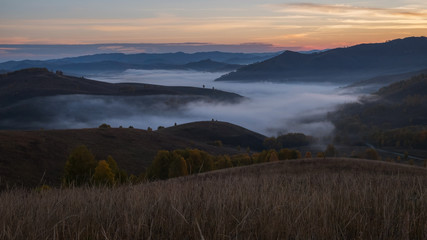 Morning fog in a mountain valley before sunset. Autumn Altai.