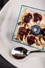 Cropped shot of one-person dessert in glass square bowl on white plate with teaspoon, close-up