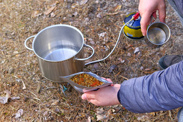 Traveler is eating freeze dried food during camping. Enjoy a tasty food during the travel holidays....
