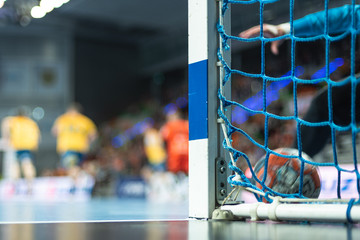 Detail of handball goal post with net and handball match in the background.