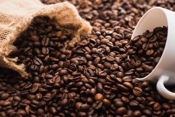Fototapeta premium selective focus of fresh roasted coffee beans and white cup near sack