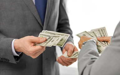 business, people and finances concept - close up of businessmen's hands holding american dollar money