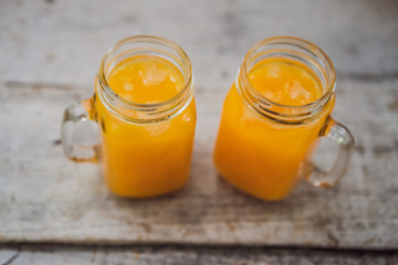 Orange juice in mason jar on wooden background