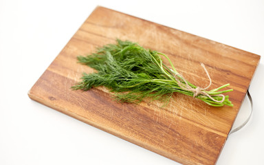 greens, culinary and ethnoscience concept - bunch of dill on wooden cutting board