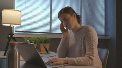 Tired woman with headache working with a laptop