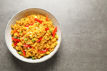 Delicious rice pilaf with vegetables on grey table, top view. Space for text