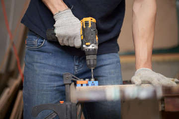 Man carpenter with drill and board in workshop