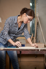 Girl carpenter in glasses with tape measure and blackboard