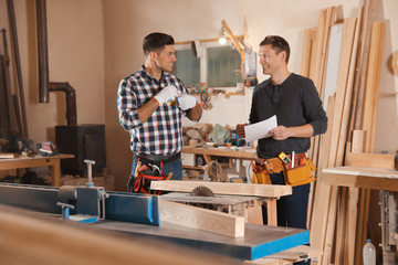 Professional carpenters working with draft in workshop