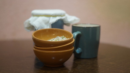 Obraz na płótnie Canvas a blue earthenware jug and mug, small brown saucers with grits on a dark background