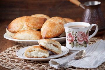 Cottage cheese pies in a plate and cup with coffee
