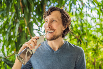 Young man uses an oral irrigator to brush his teeth