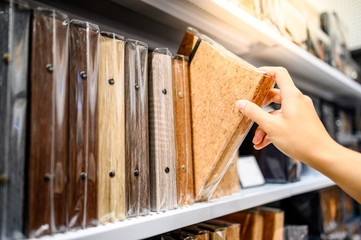 Male hand choosing new ring binder file folder with white cork board texture from shelf display in stationery shop. Buying office supplies concept