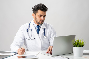 Handsome doctor sitting at desk in office