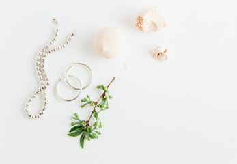 Obraz na płótnie Canvas Feminine accessories,marshmallow and green branch on white background.Beauty blog concept.For magazines and social media.Woman fashion jewelry.Flat lay.