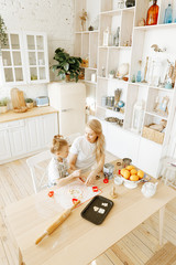 mom and daughter cook cookies together in the kitchen.