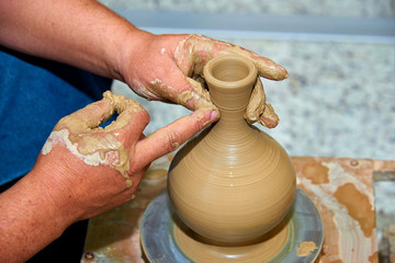 Hands of a potter. Potter making ceramic vase on the pottery wheel.