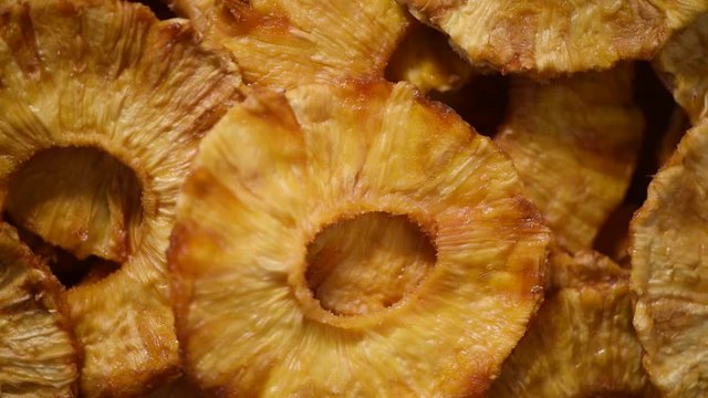 Slices of dried pineapple on rotating background. Top view. Vegan, vegetarian diet. Healthy lifestyle. Dried fruits background. Sweet pineapples, organic food.